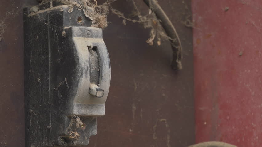 turning on an old circuit breaker black, man's hand in the switchboard turns on an old black circuit breaker dirty and covered in cobwebs
