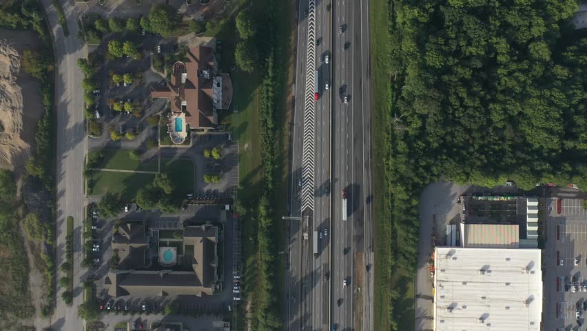 Aerial view of a busy highway cutting through lush greenery, alongside buildings with pools, the scene is vibrant and dynamic, Greenville, South Carolina, United States.