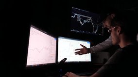 Two young traders discussing crypto trading charts growth using pc computer. Male brokers analyzing financial risks and investment profit forecast at night. Concept of stock market and data analysis - Powered by Shutterstock - Get 15% off with code: PIKWIZARD15