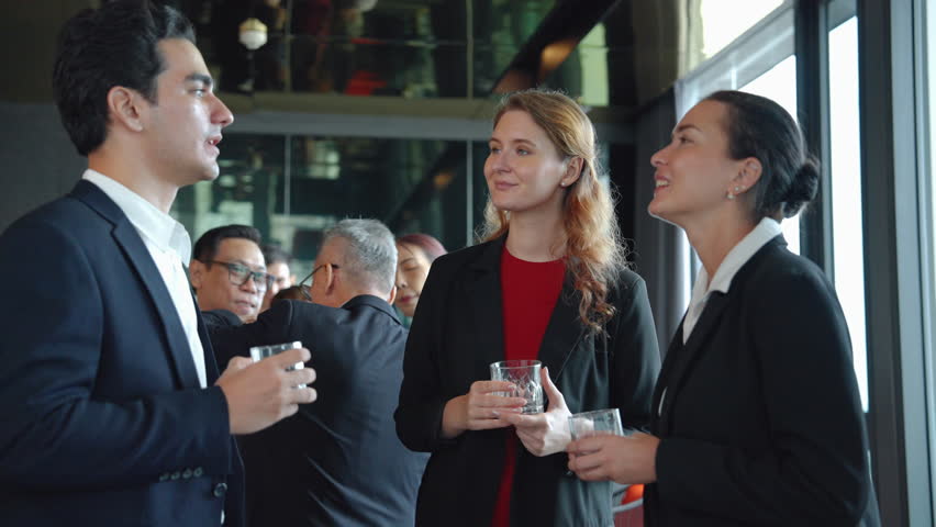 Businesspeople stand and chat in a hotel reception room after a successful cooperation meeting.