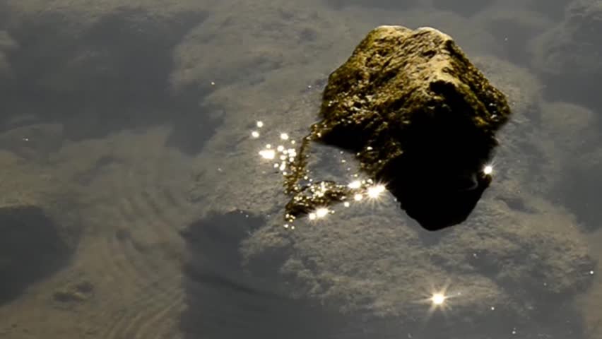 stone within a lake with sun rays, zoom out