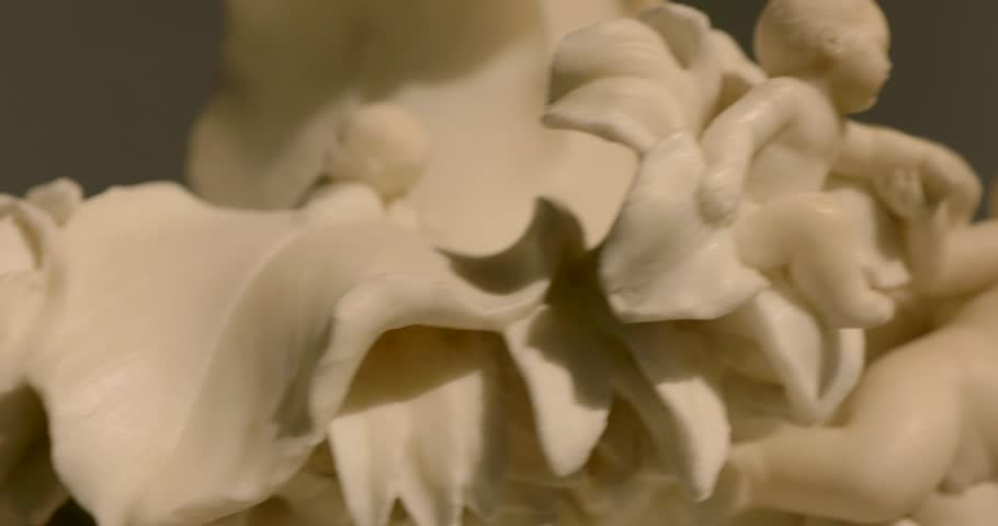 Close up of an ivory cherub statue sitting on a flower and holding another cherub's hand
