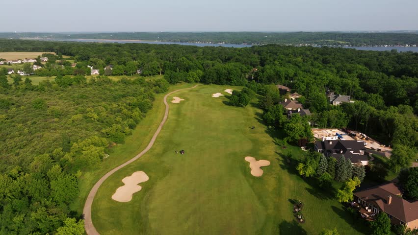 Golf course greens and tee boxes viewed from above with neat striped mowing lines and sand traps