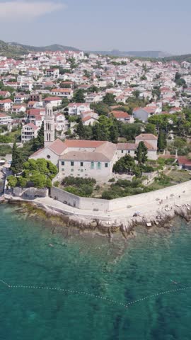 Aerial view of the Franciscan Monastery on the coast of Hvar Island, Croatia, showing the beautiful turquoise Adriatic Sea. Vertical Video
