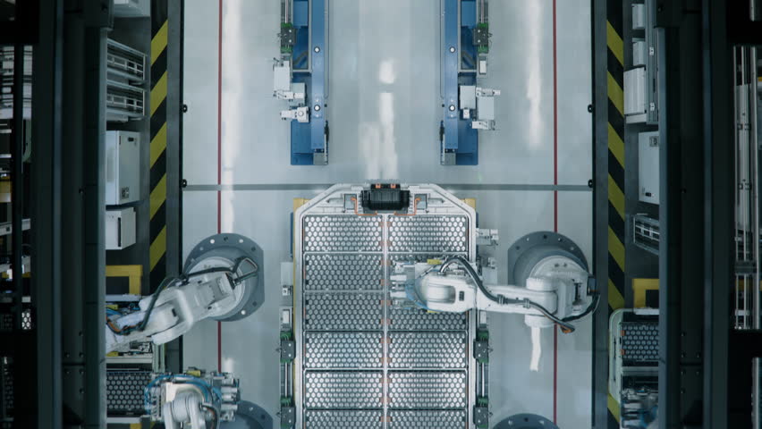 Time-Lapse of Industrial Robot Arms Assemble Lithium-Ion EV Battery Pack for Automotive Industry. Smart Automated Manufacturing. Top View of Production Line with White Robotic Arms at Factory. 