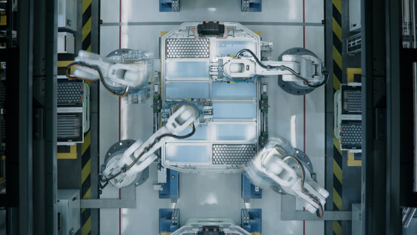 Time-Lapse of Industrial Robot Arms Assemble Lithium-Ion EV Battery Pack for Automotive Industry. Smart Automated Manufacturing. Top View of Production Line with White Robotic Arms at Factory. 