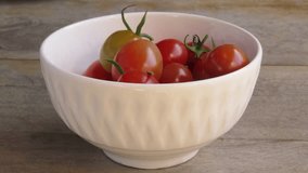 Fresh small ripe tomatoes falling in a white ceramic bowl. Red tomatoes in a bowl. Rustic wooden surface. - Powered by Shutterstock - Get 15% off with code: PIKWIZARD15