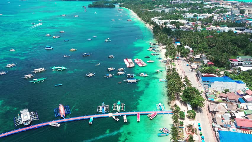 Aerial of Boracay, Philippines showcasing vibrant turquoise waters, anchored boats, and palm-lined coastline. Perfect for travel, tourism, and tropical paradise visuals.