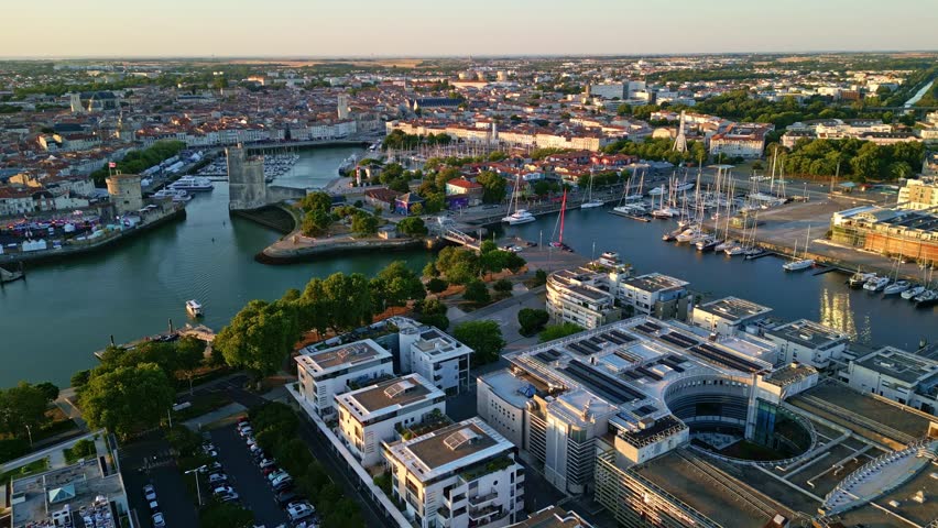 La Rochelle, Old Port and marina at golden hour, historic towers, sailboats, and cityscape, France. Aerial forward