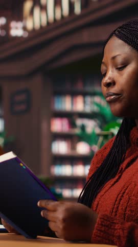 Vertical Video Focused woman in a study area reading and researching for master degree, reflecting the determined lifestyle of a student reaching academic and personal goals. Knowledge. Camera B.