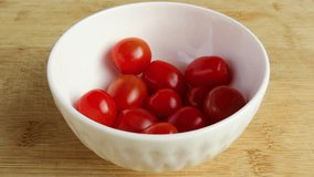 Fresh small ripe tomatoes falling in a white ceramic bowl. Red tomatoes in a bowl. Rustic wooden surface. - Powered by Shutterstock - Get 15% off with code: PIKWIZARD15