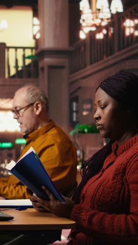 Vertical Video Colleagues disturbing a woman with their loud reading in the library, african american pupil making a noise complaint and being disturbed by the disrespect. Breaking the rules. Camera A