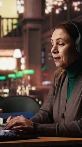 Vertical Video Mature woman involved in a remote classroom experience via online platform, using wireless internet to study a university course and chatting with his teacher. Reviewing project