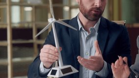 Ecology project businessman Caucasian man engineer holding mini windmill model turbine explaining asian business woman diverse collegues concept natural green energy technology investor environment  - Powered by Shutterstock - Get 15% off with code: PIKWIZARD15