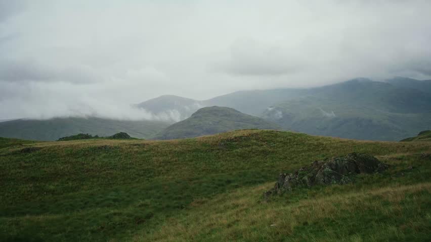 Two hiker friends sit on a rock and watch the clouds blow over the mountains