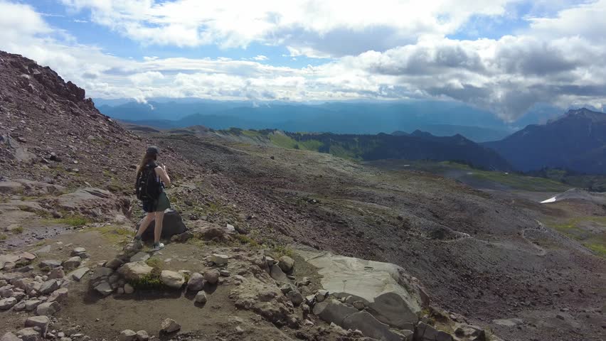 A hiker explores the rugged trails of Paradise Mt Rainier National Park, Washington USA, showcasing the breathtaking landscape.