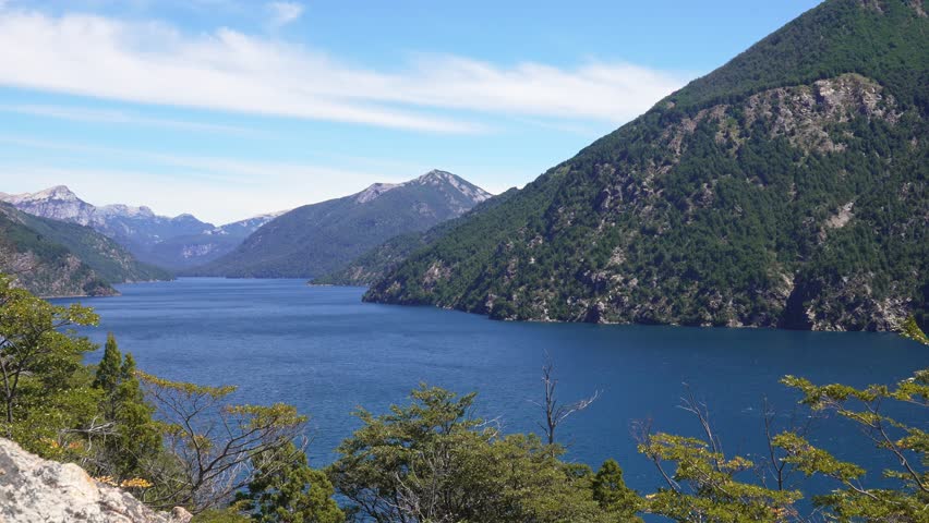 Scenic static view of Nahuel Huapi lake surrounded by rugged peaks and dense forest in Nahuel Huapi National Park. Brazo de la Tristeza from Bahia Lopez.