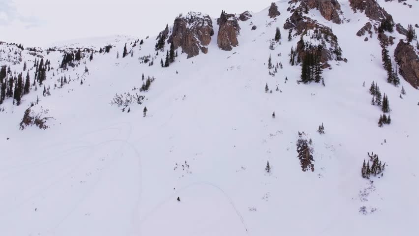 Spring cornice rock walls chute Deer Creek Trail Montezuma winter Rocky Mountain Colorado avalanche terrain aerial drone cloudy sky deep powder snow snowmobile ski snowboard backcountry forward up