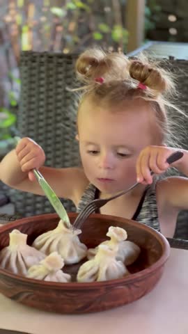 Cute child eating Georgian dumplings in a cafe during vacation. Concept of family holiday, hotel lifestyle, restaurant dining and food tourism