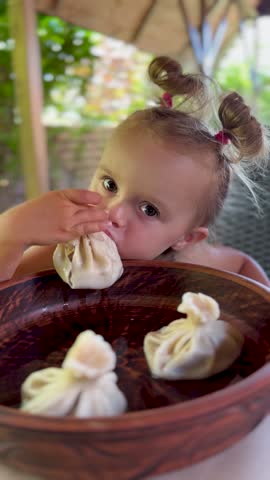 Little girl enjoys khinkali in a cozy restaurant. Perfect for travel blogs, family lifestyle and Instagram food content