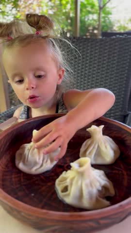 Little girl enjoys khinkali in a cozy restaurant. Perfect for travel blogs, family lifestyle and Instagram food content