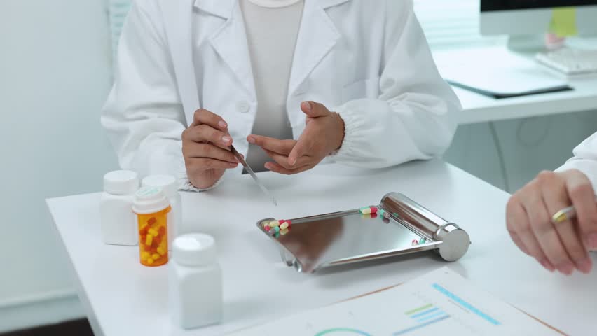 Skilled pharmacist wearing lab coat carefully picking capsules with tweezers while explaining medication dosage details to attentive patient during healthcare consultation in pharmacy setting