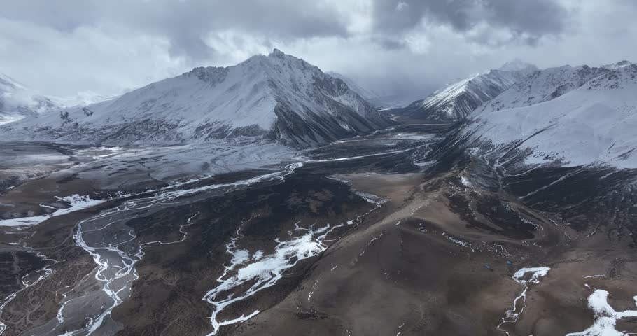 Aerial footage of beautiful high altitude snowcapped mountains and forest landscape