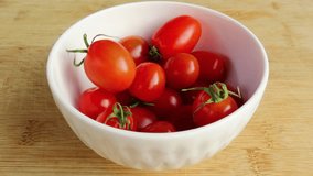 Fresh small ripe tomatoes falling in a white ceramic bowl. Red tomatoes in a bowl. Rustic wooden surface. - Powered by Shutterstock - Get 15% off with code: PIKWIZARD15