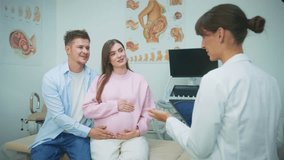 Happy Caucasian couple expecting baby while sitting together in gynecology office during consultation. Man embracing pregnant woman. Holding belly while doctor with tablet talking to them. - Powered by Shutterstock - Get 15% off with code: PIKWIZARD15