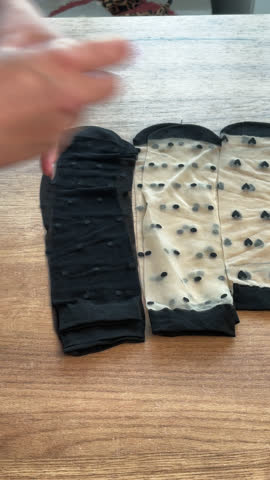 Woman reviews womens stockings. Lays them out on the table. Vertical video. Close-up.