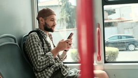 Young man sitting on a bus seat, using smartphone while commuting. Passenger traveling in public transport with modern technology. Horizontal 4k slow motion footage - Powered by Shutterstock - Get 15% off with code: PIKWIZARD15