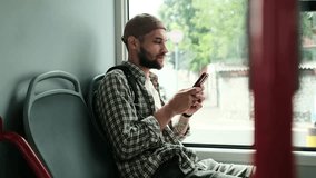 Young man sitting on a bus seat, using smartphone while commuting. Passenger traveling in public transport with modern technology. Horizontal 4k slow motion footage - Powered by Shutterstock - Get 15% off with code: PIKWIZARD15