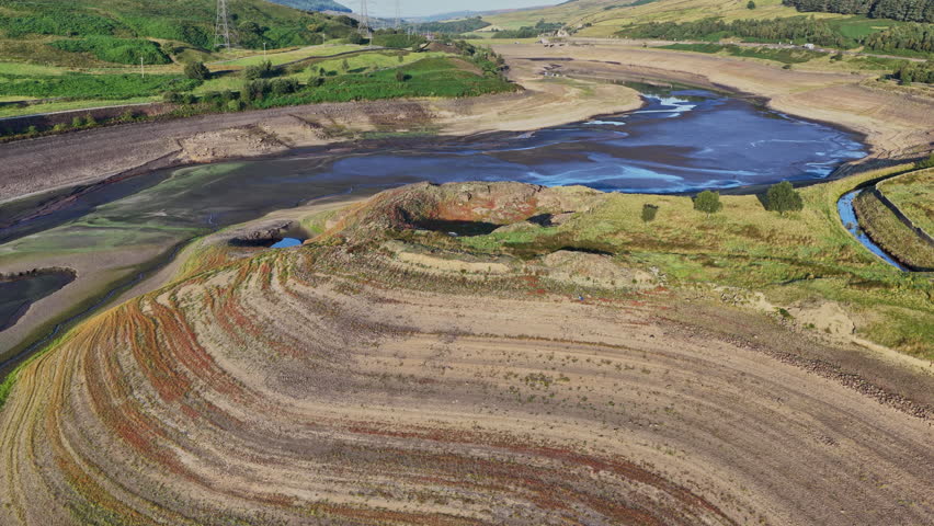 Stunning aerial footage reveals the impact of drought on Woodhead Reservoir in Derbyshire, showcasing significantly low water levels and exposed dry ground. This parched landscape highlights pressing 