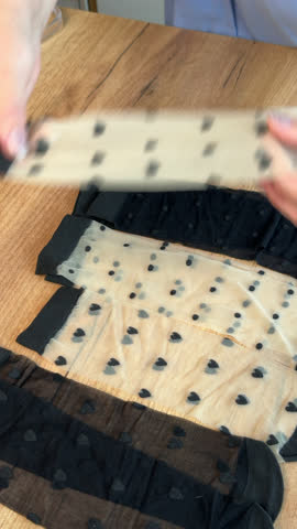 Woman reviews womens stockings. Lays them out on the table. Vertical video. Oblique Angle. Close-up