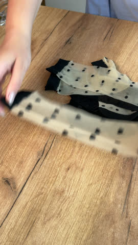 Woman reviews womens stockings. Lays them out on the table. Vertical video. Oblique Angle. Close-up.