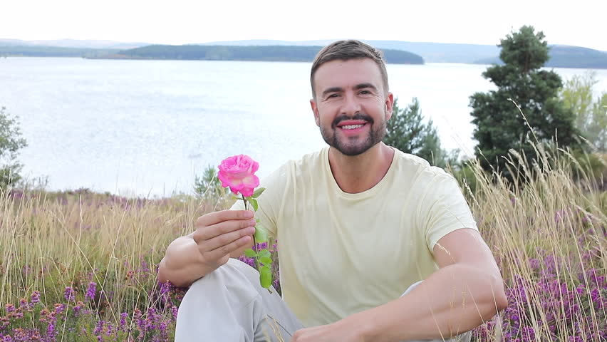 Man smelling a flower in stunning natural setting 