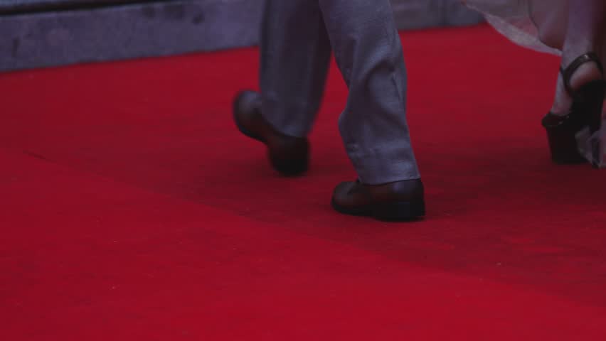 Red carpet with ropes and golden barriers on a luxury party entrance, cinema premiere film festival event award gala ceremony, wealthy rich guests arriving, outdoor decoration elements, summer day