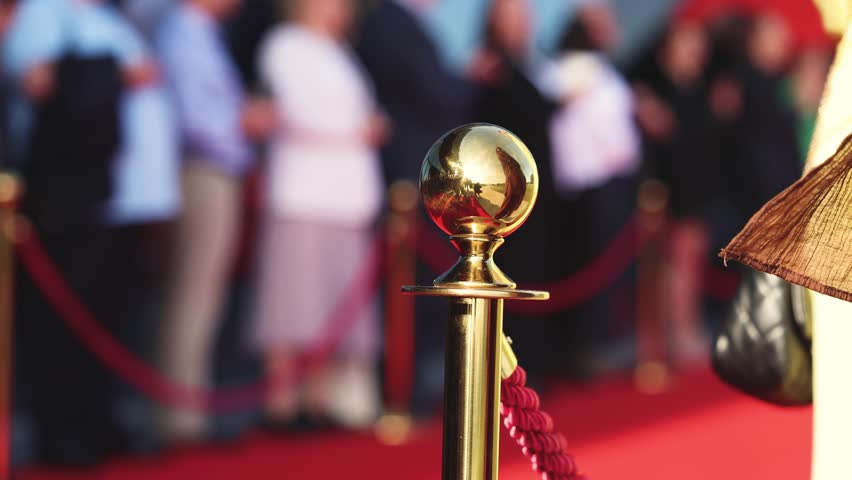 Red carpet with ropes and golden barriers on a luxury party entrance, cinema premiere film festival event award gala ceremony, wealthy rich guests arriving, outdoor decoration elements, summer day
