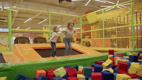 Two little girls playing on indoor playground in foam rubber pit in trampoline, active pastime in the amusement park. Slow motion - Powered by Shutterstock - Get 15% off with code: PIKWIZARD15