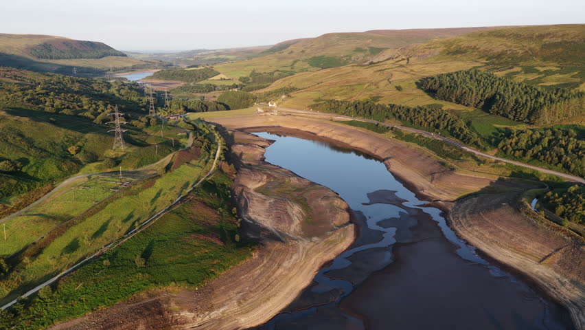 Stunning aerial footage reveals the impact of drought on Woodhead Reservoir in Derbyshire, showcasing significantly low water levels and exposed dry ground. This parched landscape highlights pressing 