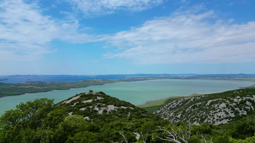 Panoramic view from Vidikovac Kamenjak, the highest point above Vransko Lake Nature Park in Croatia. The viewpoint offers breathtaking views of the Adriatic Sea, surrounding islands, and Dalmatia