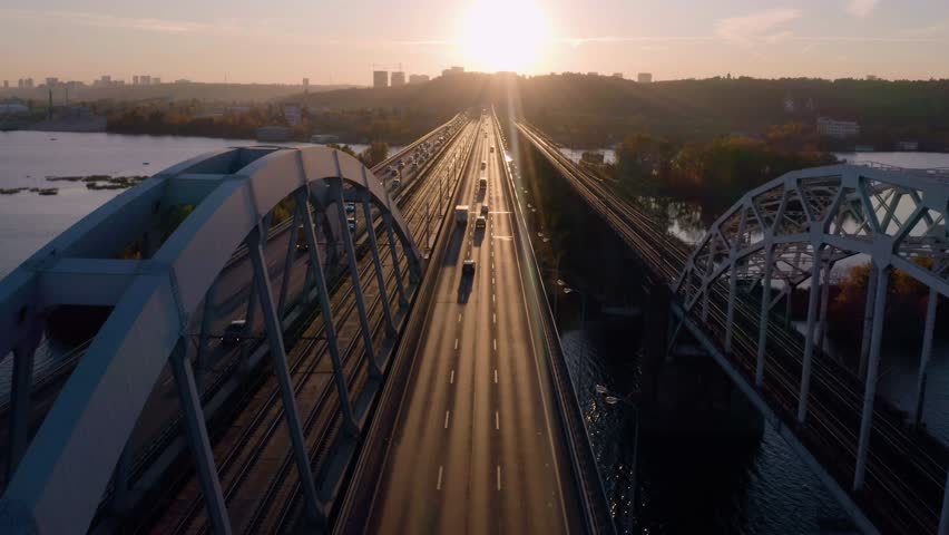 Cars moving on picturesque bridge over river. Aerial panoramic view from drone. Beautiful autumn city landscape.