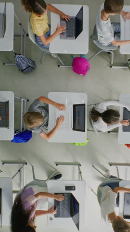 Elementary School Children Using Laptops, Creating Drawings During Digital Art Lesson. Young Students Doing Creative Tasks on Digital Gadgets. Interactive STEM Education. Top View. Vertical Shot.