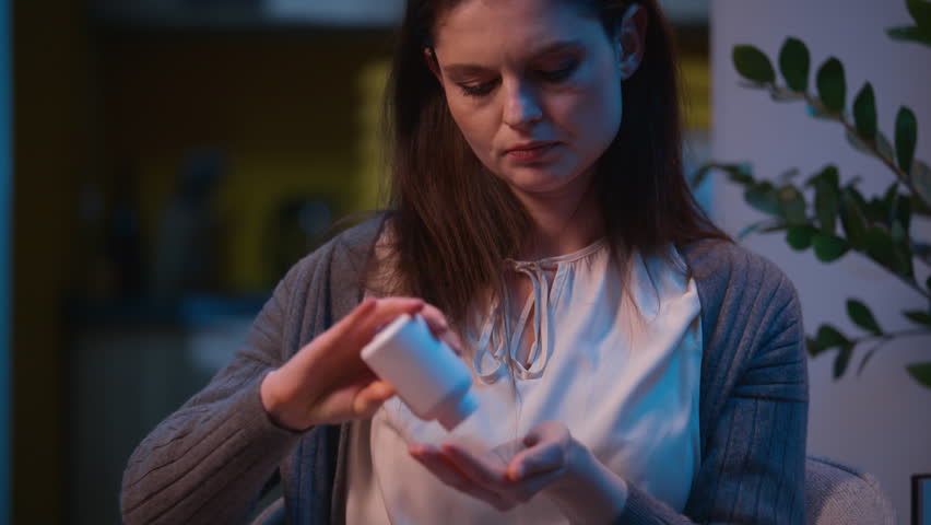 Upset depressed woman sad female housewife at night home worried girl drink pills drugs addicted health problem suffer sick unhealthy medication painkiller antidepressant stress empty medicine bottle