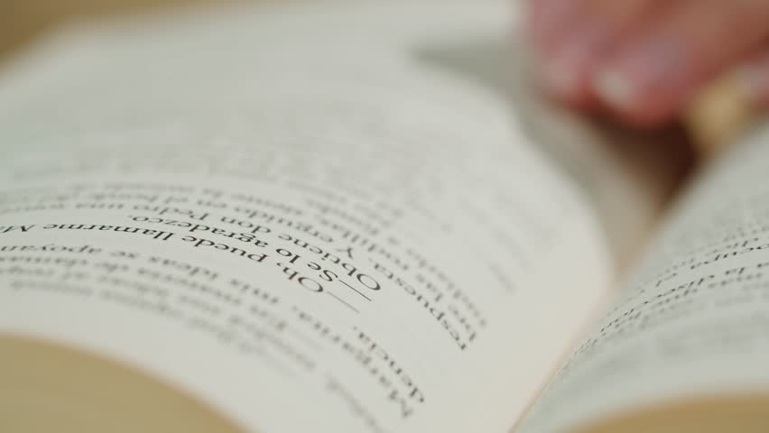Flipping Spanish language book pages, reading and education, Flicking Through Old textbook Close-up, macro shot of paper in university library.