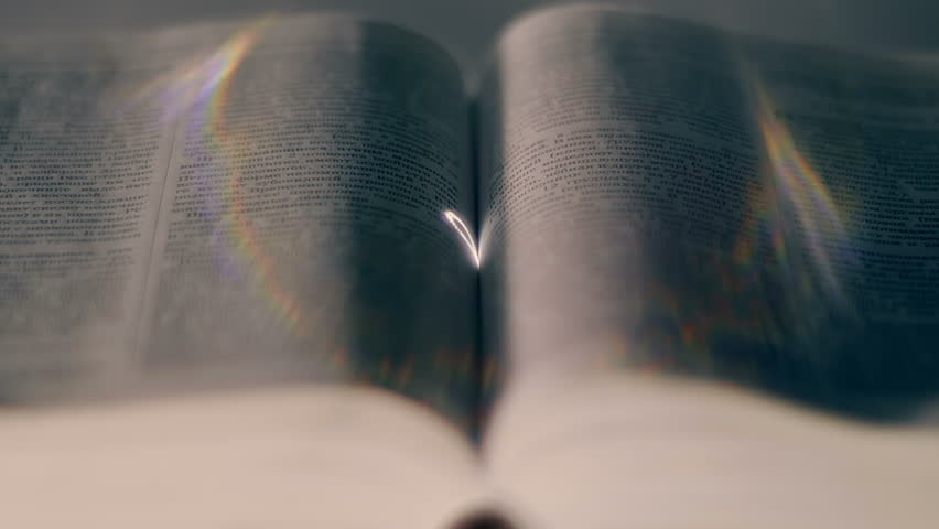 A thick open book lies on a table, a circular ring is projected onto the pages to form a heart. Closeup