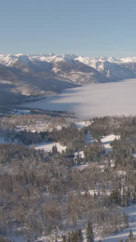 AERIAL: Beautiful aerial view of a fog covered valley in the snowy Julian Alps. Flying around the snowy wilderness high in the backcountry of Slovenian mountains. Gorgeous alpine scenery from above.