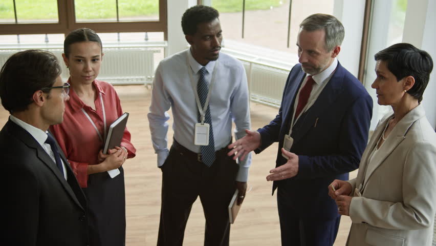 Young elegant businessman in formalwear shaking hands of intercultural delegates after indroducing himself during meeting of colleagues after business conference