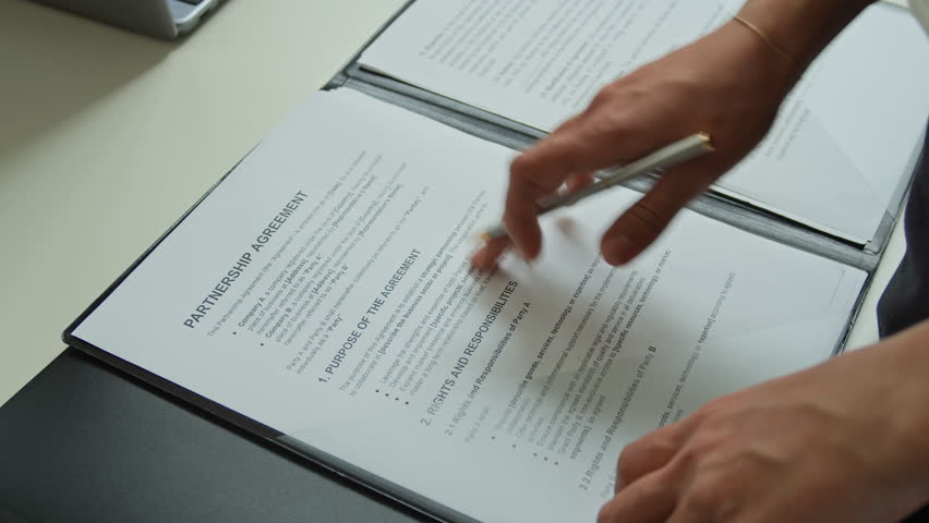 Hands of young unrecognizable female business coach with pen looking through main points of report, pointing at most significant of them and circling and underlining them