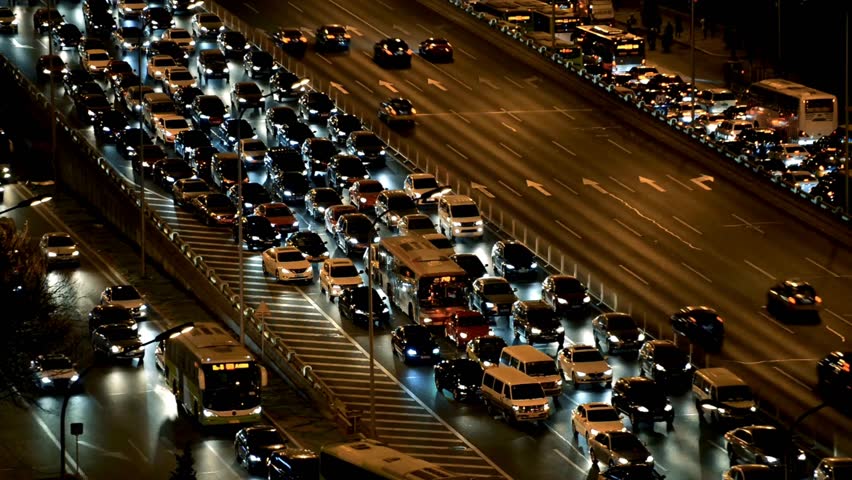 High angle Shot of cars traffic transportation during sunset to night on a city. Cars are stuck in slow moving heavy traffic jam on the city roads.